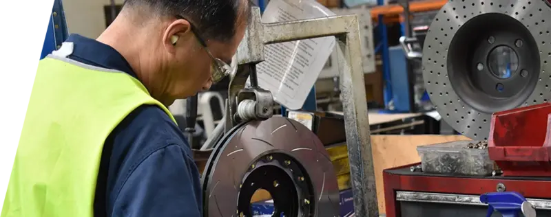 Technicien d'usine DBA en équipement de sécurité travaillant sur la production de disques de frein avec équipement spécialisé