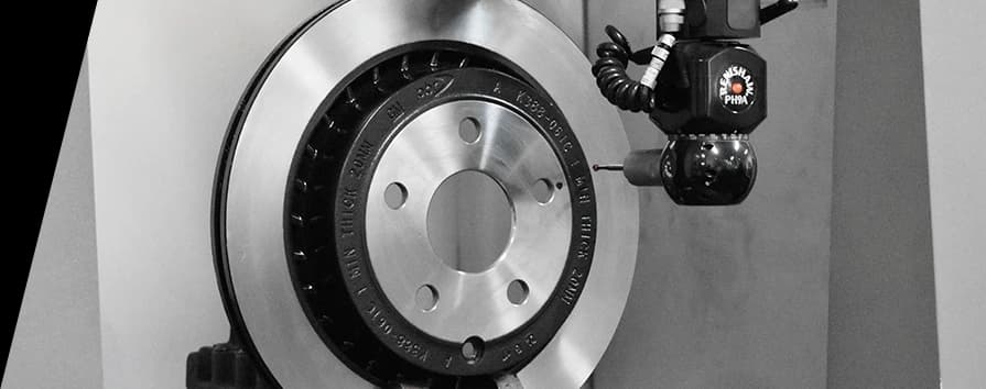 Gros plan en noir et blanc d'un disque de frein DBA dans une installation de fabrication avec équipement spécialisé positionné près de la surface lisse du disque