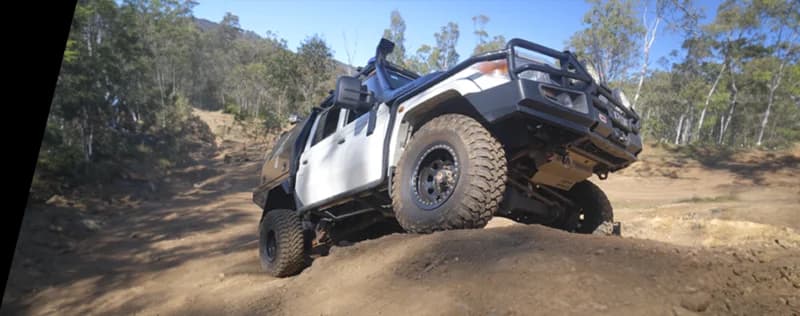Véhicule 4WD blanc positionné sur pente sableuse raide en terrain de brousse australienne démontrant capacité tout-terrain