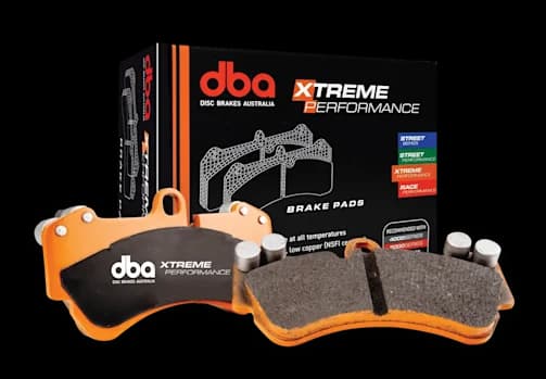 Plaquettes de frein DBA Xtreme Performance avec plaques de support oranges et matériau de friction présentées avec leur boîte d'emballage