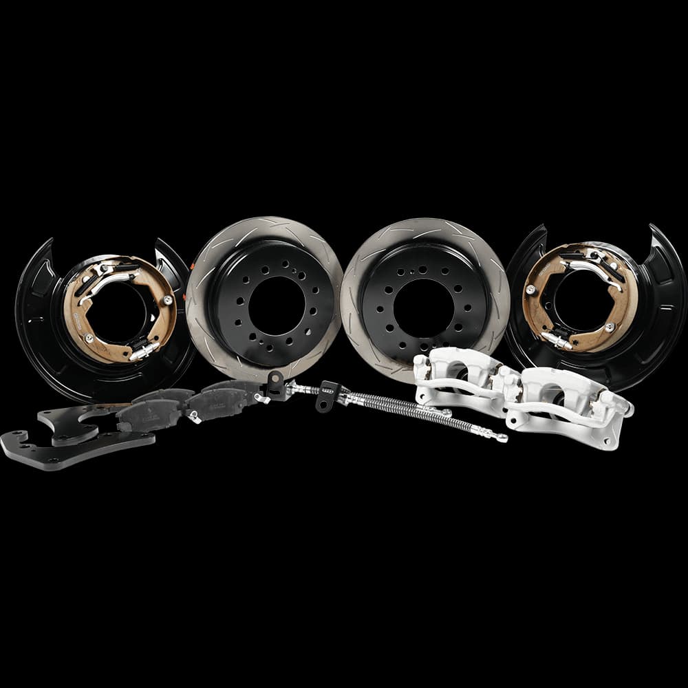 Kit conversion freins tambour vers disque complet montrant rotors freins, étriers, mâchoires frein, flasques support et composants hardware sur fond blanc