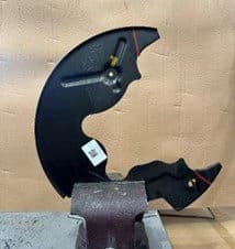 Étape 3A: Plaque support retirée du véhicule et fixée dans un étau pour coupe le long des lignes marquées pour l'espace de l'étrier DBA Plaque support retirée positionnée dans un étau montrant les lignes de coupe marquées au stylo prêtes pour modification pendant l'installation